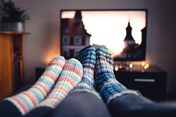 couple with warm socks sitting in front of the tv