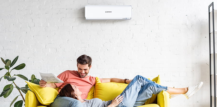 young couple sitting on lounge underneath heat pump