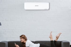 woman on couch underneath mitsubishi heavy industries split system heat pump